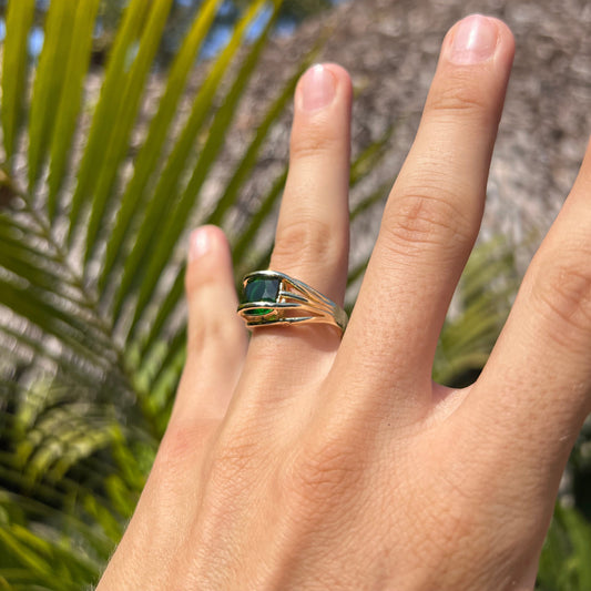 Anillo con diseño de barras sujetando una piedra verde.