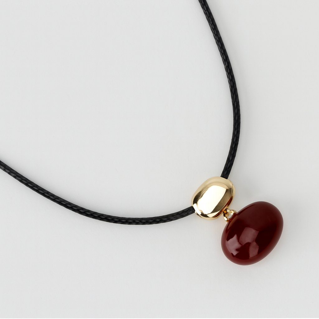 Collar con dije de piedra roja y cuenta dorada en cordón negro