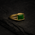 Anillo con diseño de barras sujetando una piedra verde.